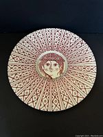 Front view of the charger showing the red and white intricate radiating pattern with a central face motif.