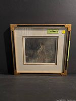 Front side with woman figure in long dress in muted colors behind glass in wooden frame with matting