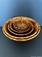 Stacked view showing all four nested bowls with brown and tan spatter glaze finish