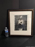 Full view of framed etching print next to a water bottle for size reference.