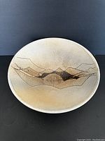 Top-down view of shallow ceramic bowl showing mountain design interior and beige matte glaze.