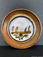 Front view showing the circular plate with brown rim and painted flower design in center