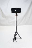 Front view of JOBY TelePod selfie stick tripod with smartphone mounted, tripod legs open on white background.