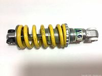 Close-up image of yellow coil spring shock absorber with metal ends and adjustment ring.