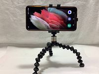 Black flexible GorillaPod tripod with smartphone mounted horizontally showing screen