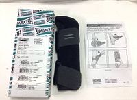 Photo of the wrist brace, its original packaging and instruction manual showing product details and usage.