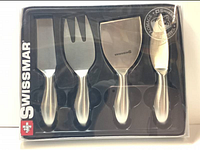 Front plastic display of new Swissmar 4-piece stainless steel petite cheese cutting utensils, showing four utensils with shiny steel handles and blades in a black tray.
