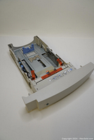 Front and side view of light gray HP paper tray showing blue and red adjustment levers and instructions sticker on front.