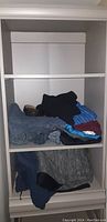 Front view of upper shelving unit holding folded clothing.