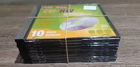 9 packs of blank CD-RW discs stacked and secured with a rubber band on wooden surface