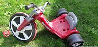 Side view of the red Big Flyer tricycle showing front wheel and seat