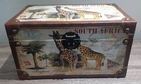 Front view of the rectangular wooden box showing giraffe artwork and metal clasp