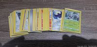 Stack of loosely arranged Pokemon cards showing the colorful fronts and some card types visible including Trainer and Pokemon cards