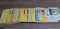 Top view of fanned out Pokemon cards showing a variety of types with yellow card borders on a wooden surface.