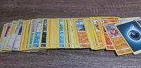 Spread out collection of Pokémon cards showing various card faces and types including energy cards and several character cards.