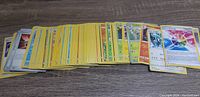 A loose stack of various Pokemon cards including Trainer and Energy cards spread on a wooden surface.