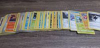 Spread out view of approximately 130 Pokemon cards showing various types including Fire, Water, Grass, and Energy with visible Trainer cards.