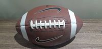 View of the brown Nike football from the front showing the white laces, white stripes, and black Nike swoosh logo