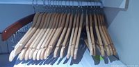 Light wooden clothes hangers closely packed on a rod.