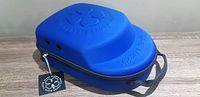 Closed view of blue hard shell hat caddy showing embossed clover design and attached tag