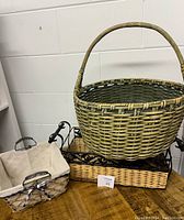 Photo showing large green vintage basket with handle, small rectangular basket with fabric liner, and rectangular basket with black metal base stacked together.