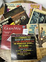 Photo displaying seven vinyl record albums arranged overlapping on a wooden surface.