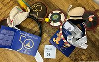 Photo of two Walt Disney World 50th Celebration Mickey ears headbands with tags and related literature on a wooden surface.