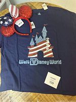 Navy blue t-shirt laid flat showing the castle graphic with American flag design and 'Walt Disney World' text.
