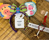 Photo showing the Disney Holiday ears headband with attached colorful bow and character pouches, along with the Forky ornament and tags on a wooden surface.