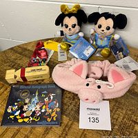 Disney themed kids bundle with plush toys, whistle, autograph book, and headband on round table