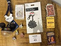 Photo showing Disney keychain, trading pins, and vintage buttons including Food & Wine Festival 2019 pin, Mickey 2000 button, character face buttons, and packaged Tomorrowland metal keychain.
