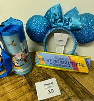Photo showing blue Minnie Mouse ears headband, Disney water bottle holder, colorful desk sign on wooden surface with lot tag 29