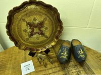 Round vintage wooden tray with scalloped edges and detailed gold and burgundy painted decorations on wooden table