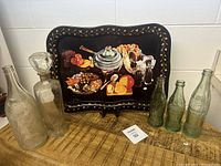 Overview of vintage glass bottles including several Coca-Cola bottles and decorative serving tray behind them