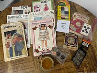 Wide view of vintage sewing patterns, pin cushion, buttons and other sewing notions arranged on a wooden surface.