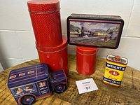 Photo showing six vintage tins including red polka dot nesting tins, Hershey's truck tin, Wright's Liquid Silver Cream tin, and rectangular train scene tin arranged on a shelf