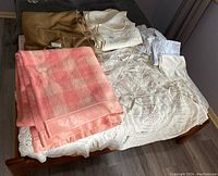 Wide view of all blankets, bedspreads, and sheet sets laid out on a bed showing the variety of textures and colors.