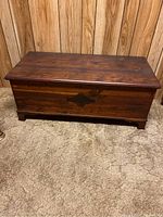 Side and slight angled view of cedar chest showing dark wood finish and scuffing on the sides and edges.