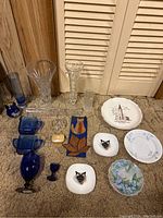 Overview of the collection showing crystal vases, cobalt blue glassware, vintage creamer and sugar, decorative plates, and stained glass decor.