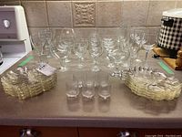 Overview of all glassware items including wine glasses, juice glasses, and flower shaped plates arranged on counter.