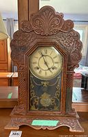 Front view of Waterbury Dabney clock in ornately carved wooden case showing entire clock body and surrounding environment.