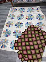 Photo showing both the Dresden Plate quilt with colorful patchwork circles and the crocheted blanket in green, pink, and brown squares laid on top.