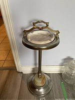 Full view of the standing ashtray showing the metal base, shaft, and marble insert with brass handle on top.
