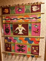 Full view of Navaho woven textile with multiple colorful sections and mounted on three wooden rods
