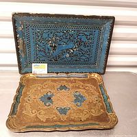 Two antique wood trays set: one gold and blue gilt with ornate design, one blue lacquered with painted figures.