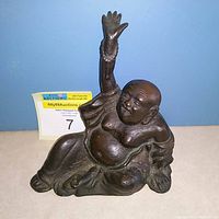 Front view of antique seated Happy Maitreya Buddha statue with raised right hand holding prayer beads.