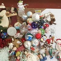 Lot showing a wide assortment of vintage Christmas ornaments including glass balls, fabric figures, and small holiday characters.