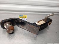 Photo showing side view of the CURT drop trailer hitch with 2-inch ball attached. The metal hitch is black with signs of wear and surface rust on the ball.