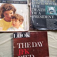 Three vintage LOOK magazines arranged on a surface. One magazine's title reads 'LOOK THE DAY JFK DIED'. Another magazine titled 'LOOK THE JFK MEMORIAL ISSUE' shows a woman and young boy on the cover. The third magazine is titled 'LOOK THE DRAMATIC CONCLUSION OF THE DEATH OF A PRESIDENT' with a blue-green cover showing an object resembling an old phone.
