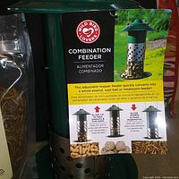 Photo shows green metal combination bird feeder with attached tag describing adjustable hopper for peanuts, suet, or mealworms.